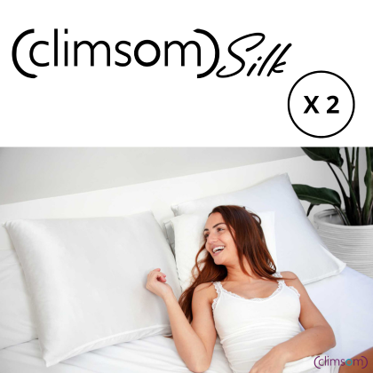 Pack de 2 taies d'oreiller en soie Climsom Silk pour un sommeil confortable et soin de la peau. Femme souriante allongée sur un lit avec des taies en soie blanche.